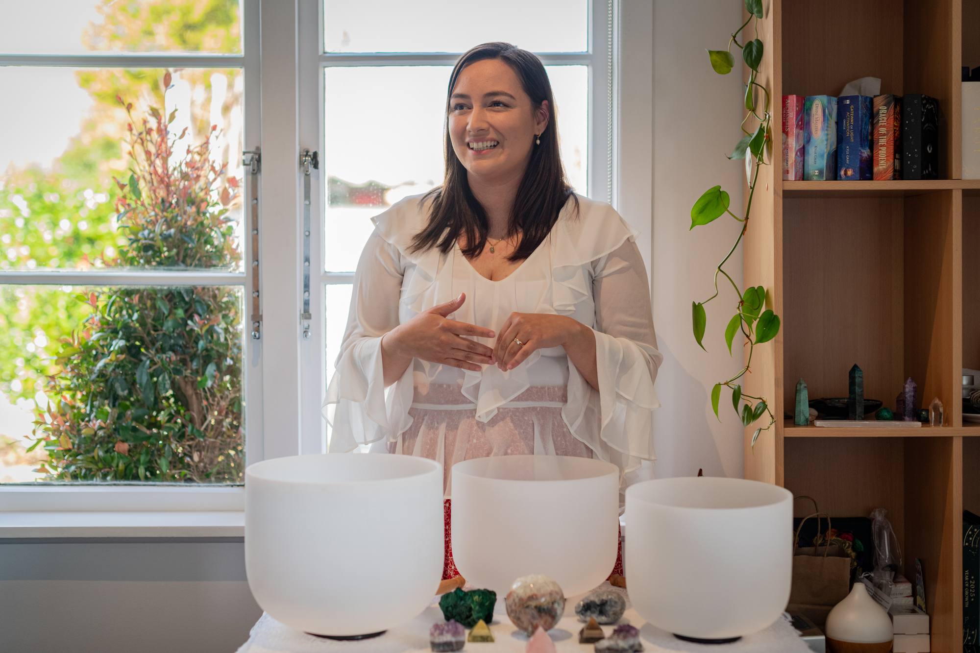 Sam smiling behind her crystal singing bowls in the Blossoming Hearts studio